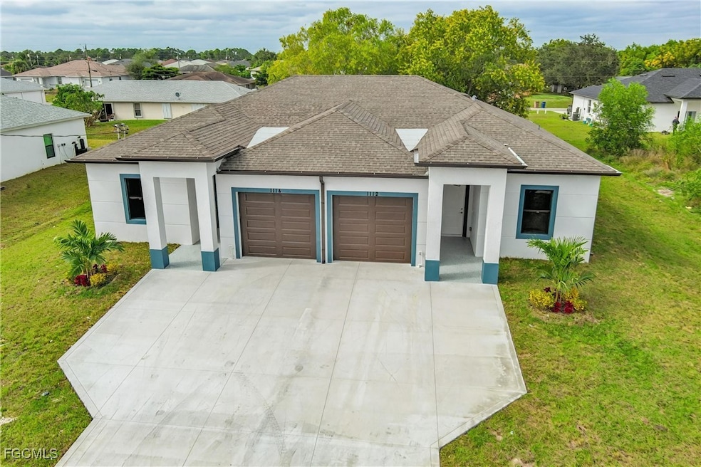 View of front of property featuring a front yard, stucco siding, a garage, and driveway