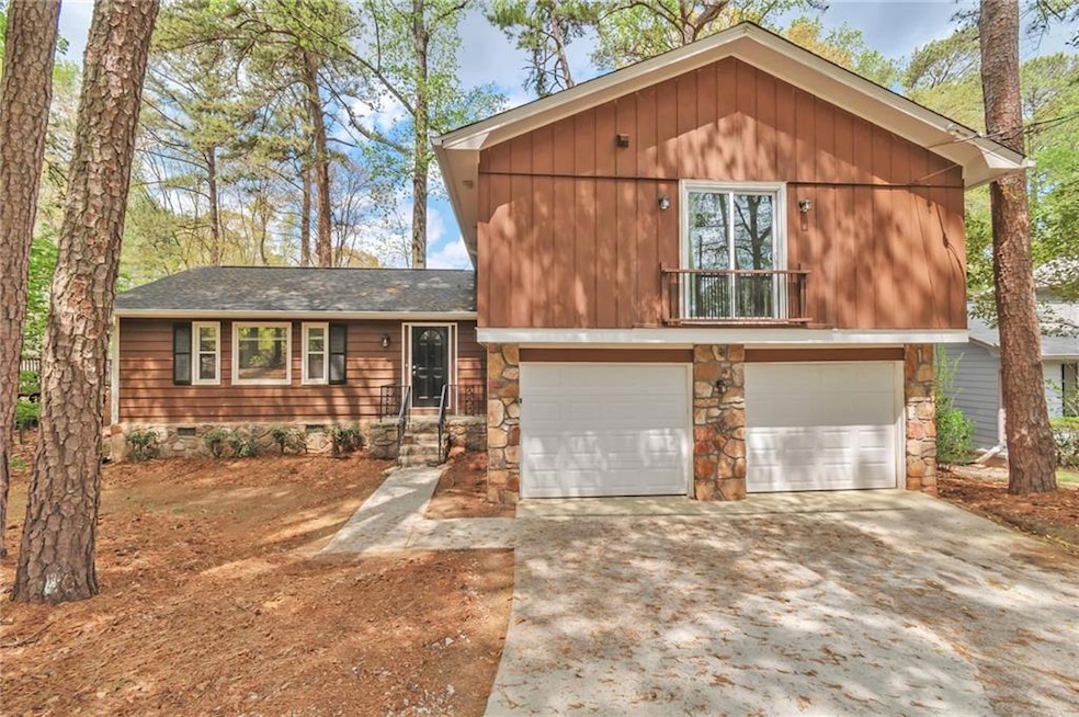 View of front of house featuring a shingled roof, crawl space, driveway, stone siding, and a garage
