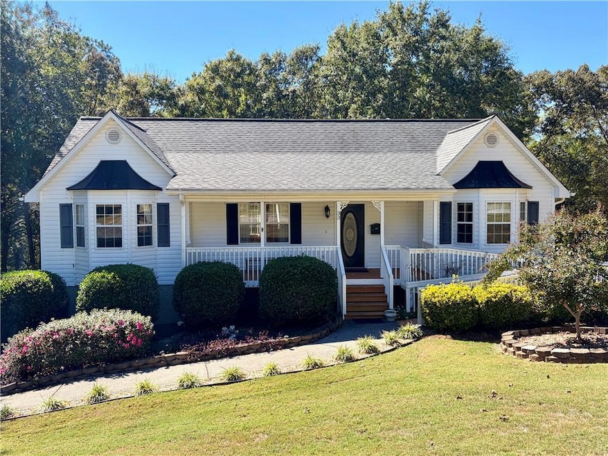 View of front of home with a porch, a front lawn, and roof with shingles