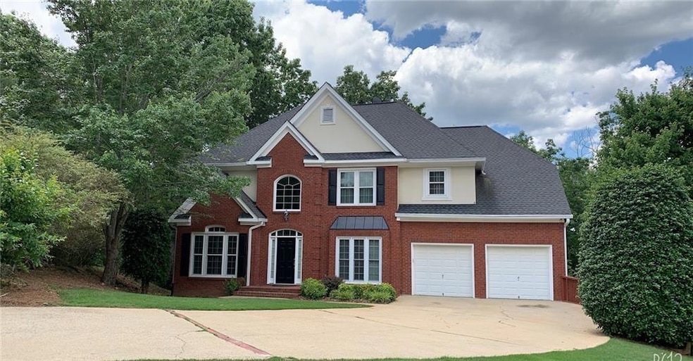 Colonial home featuring concrete driveway, brick siding, a garage, and roof with shingles