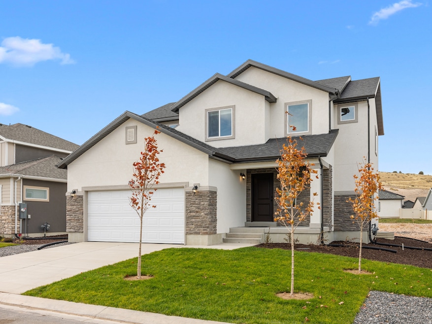 View of front of home featuring stone siding, concrete driveway, stucco siding, and a front yard