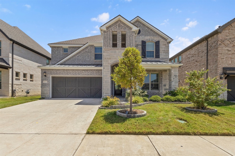 Front of the home with brick and stone siding, 2-car garage, driveway and a front lawn
