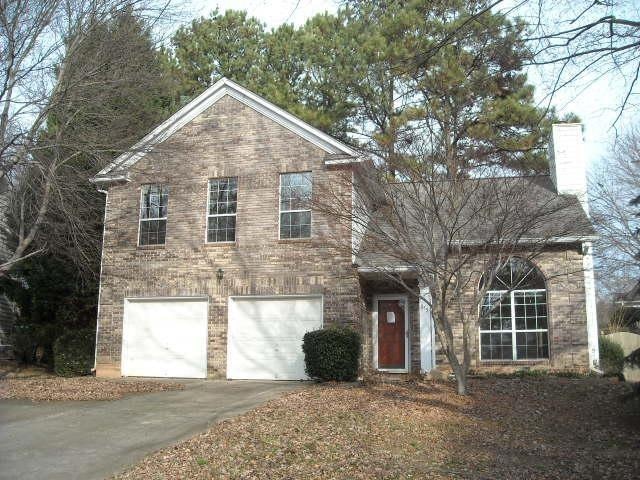 Traditional-style home featuring concrete driveway, a garage, and a chimney