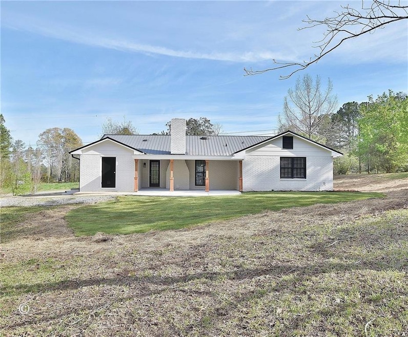 Back of house featuring a lawn, a patio, metal roo