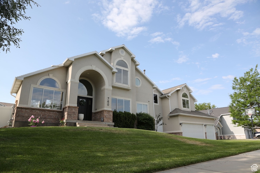 View of front of house with a front yard, stucco siding, and brick siding
