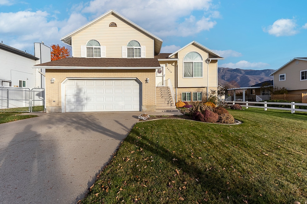 Split level home featuring a mountain view, concrete driveway, an attached garage, and brick siding