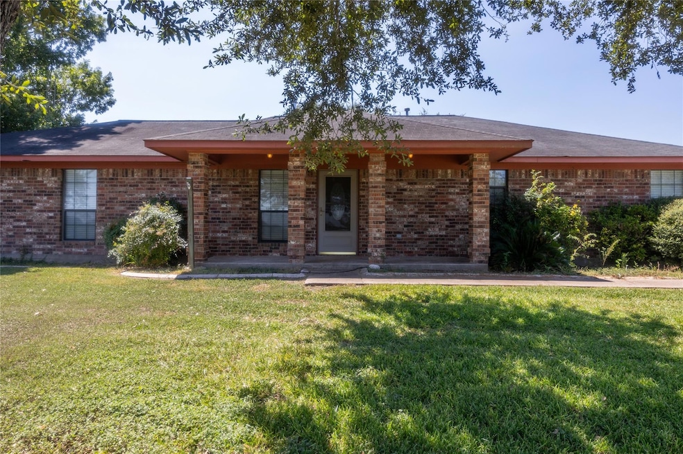 View of front facade featuring a front lawn, brick siding, and covered porch