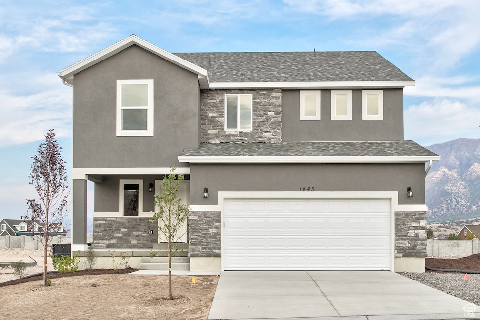 View of front of house featuring stone siding, stucco siding, and driveway