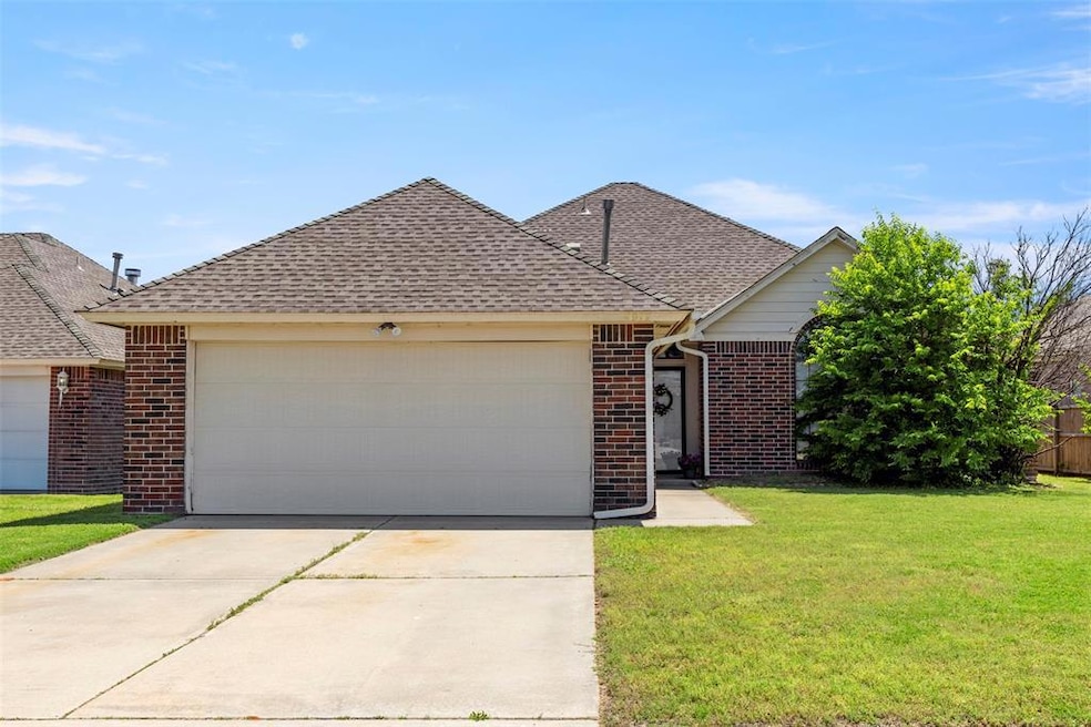 View of front of house with brick siding, a garage, a shingled roof, a front yard, and concrete driveway
