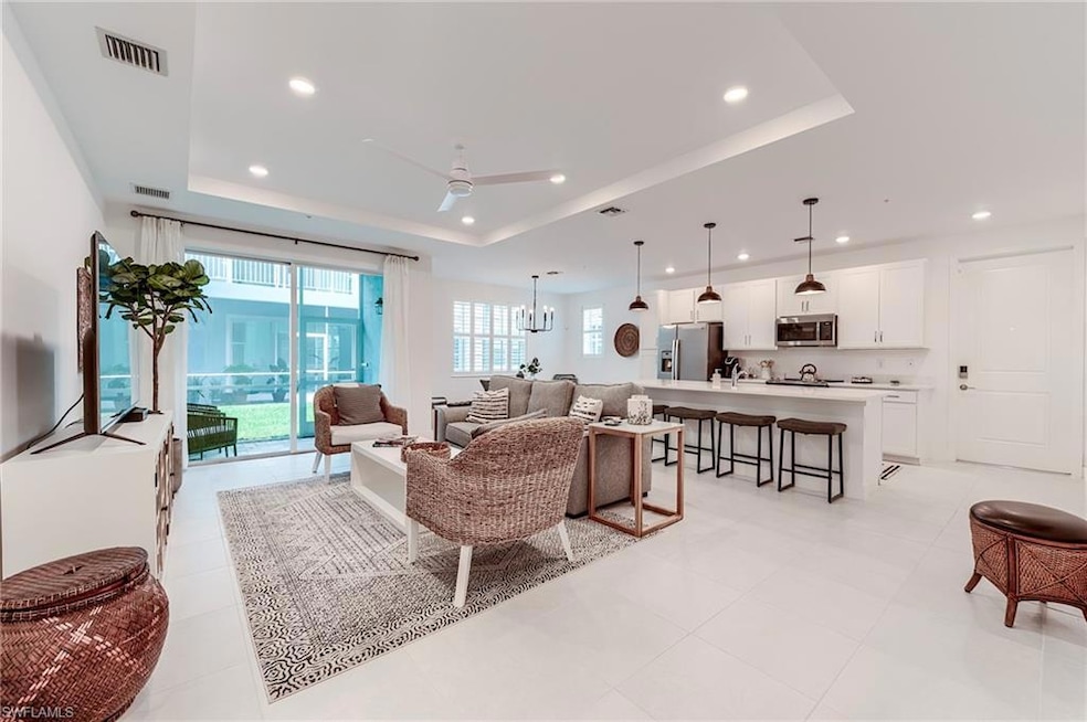 Living room with a tray ceiling, recessed lighting, a ceiling fan, and light tile patterned floors