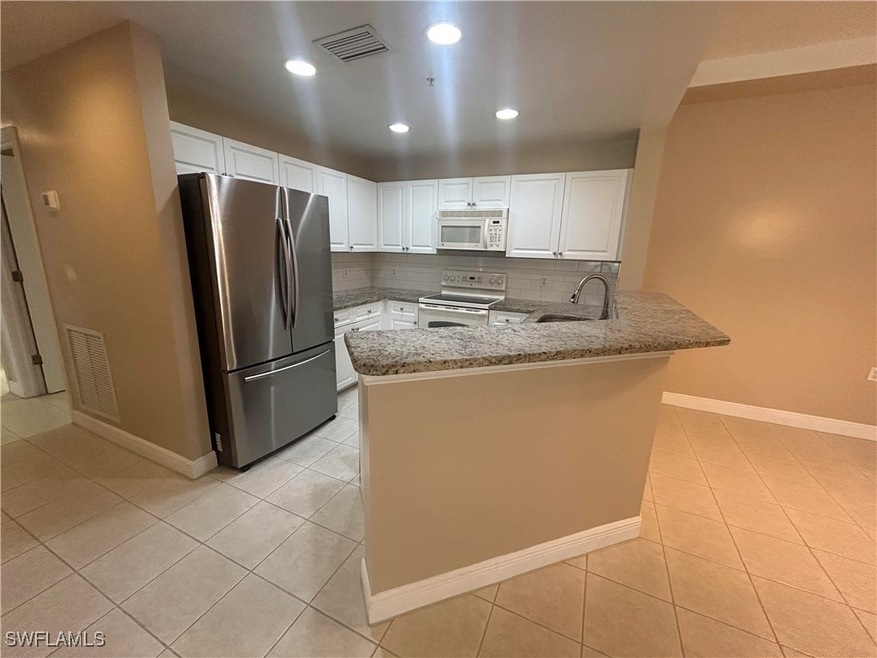 Kitchen with white appliances, a peninsula, light