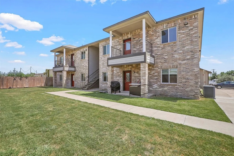 View of front facade with a balcony, brick siding, and stairway