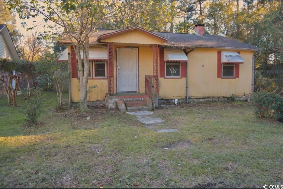 Bungalow with a front yard and a chimney