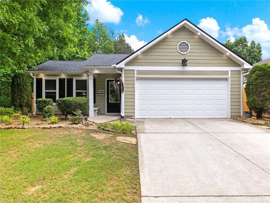 Single story home with driveway, an attached garage, a front lawn, and roof with shingles