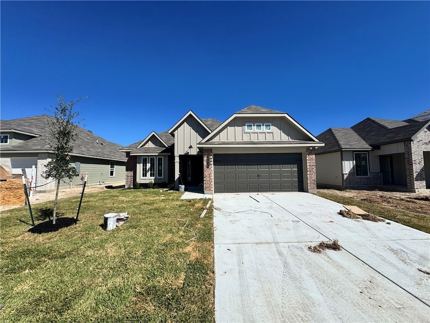 Craftsman house featuring board and batten siding, brick siding, concrete driveway, a front yard, and an attached garage