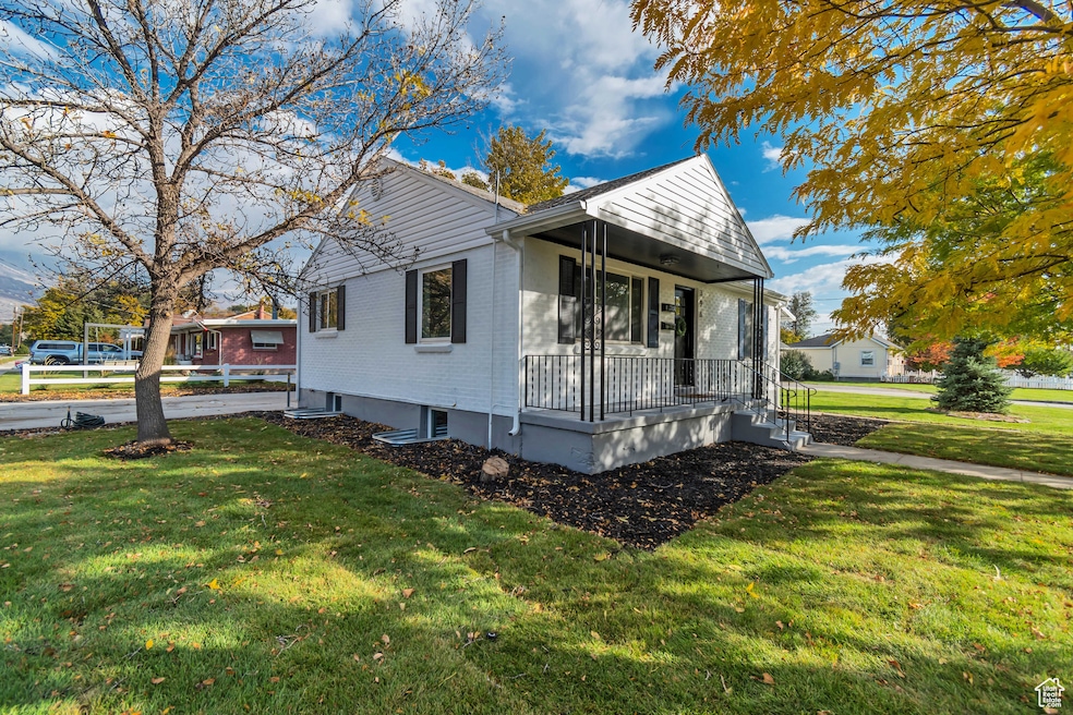 View of side of property featuring a porch, a yard, and brick siding