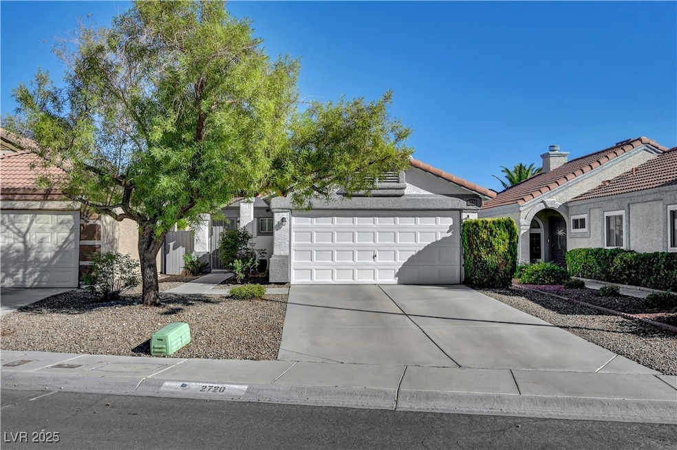View of front of house with driveway, stucco siding, a tile roof, and a garage