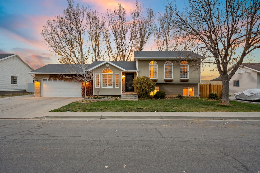 Tri-level home featuring driveway, brick siding, and a garage