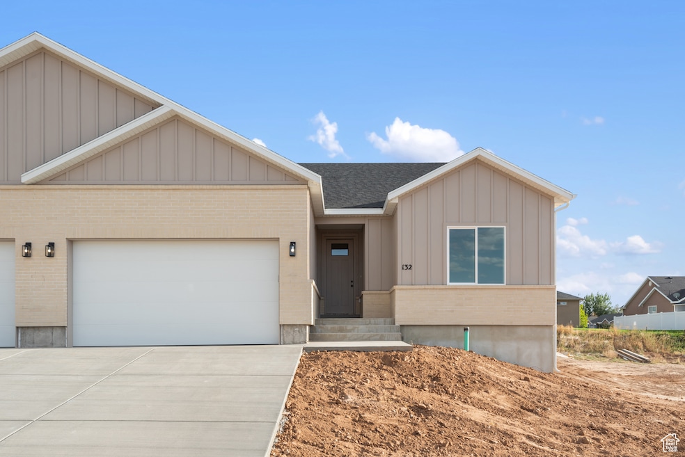 View of front of property featuring board and batten siding, brick siding, concrete driveway, a garage, and roof with shingles