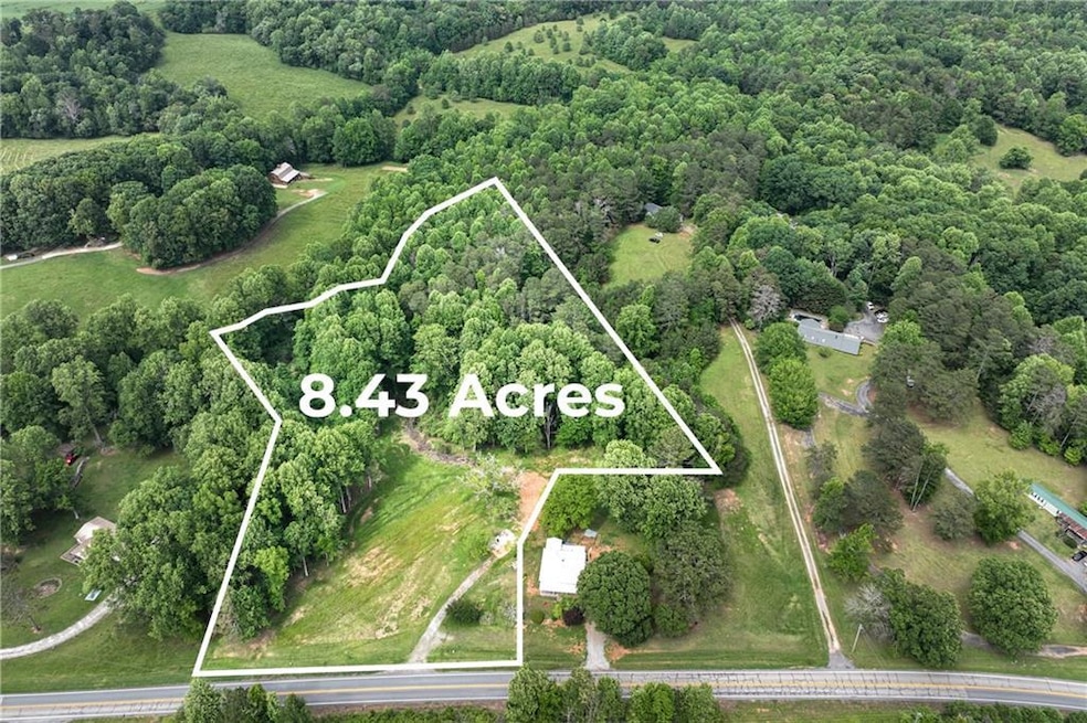 Aerial view of property and surrounding area with property parcel outlined and a forest