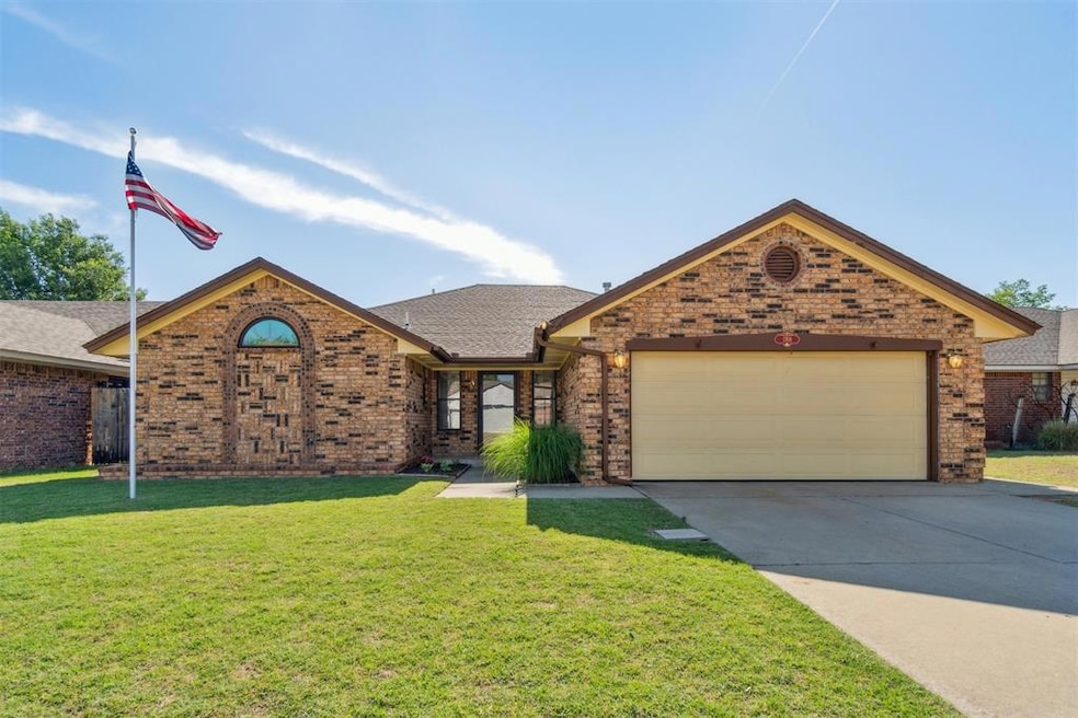 View of front of house featuring brick siding, a garage, driveway, a front lawn, and roof with shingles