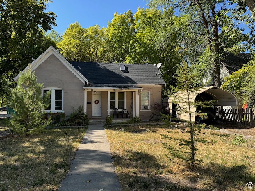 Bungalow featuring a front lawn, a carport, covered porch, and fence