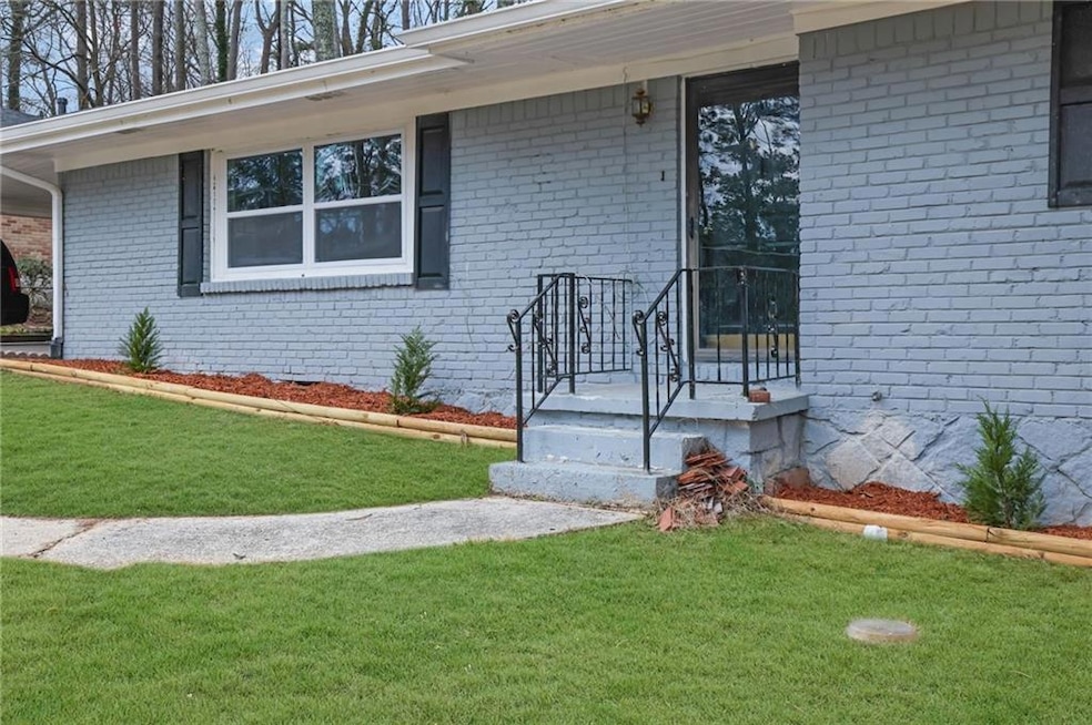 Doorway to property featuring a lawn and brick sid
