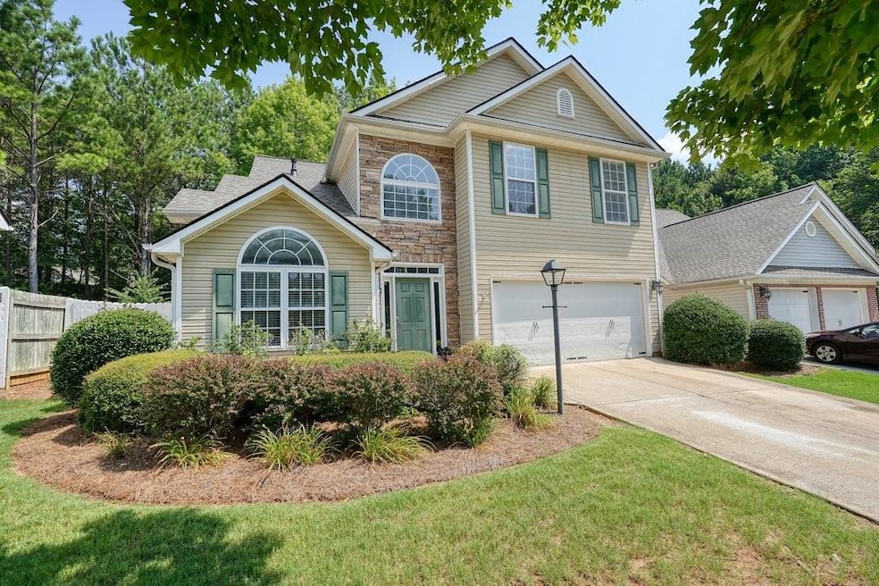Traditional-style home featuring a garage, driveway, and stone siding