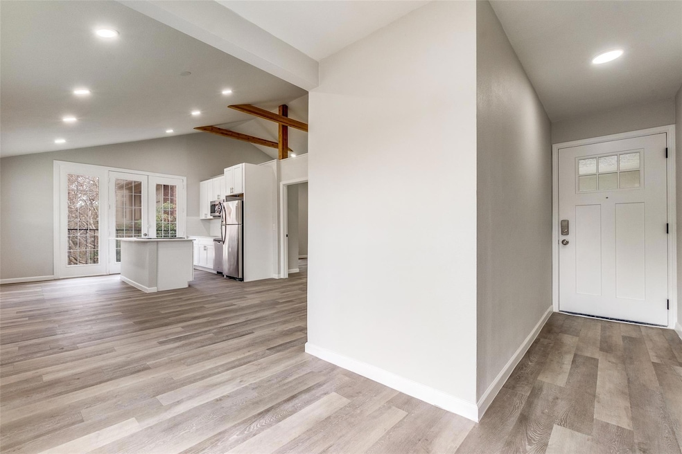 Entryway with vaulted ceiling with beams, baseboar