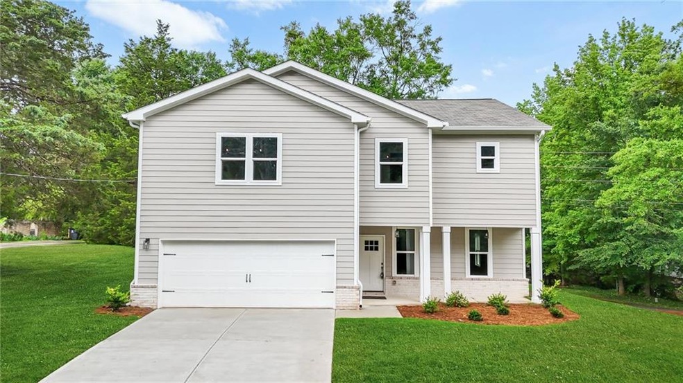 View of front of house with a garage, a front yard, driveway, covered porch, and roof with shingles