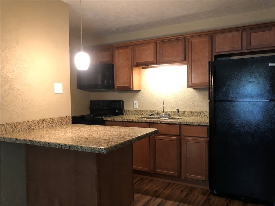 Kitchen with black appliances, a sink, dark wood-t