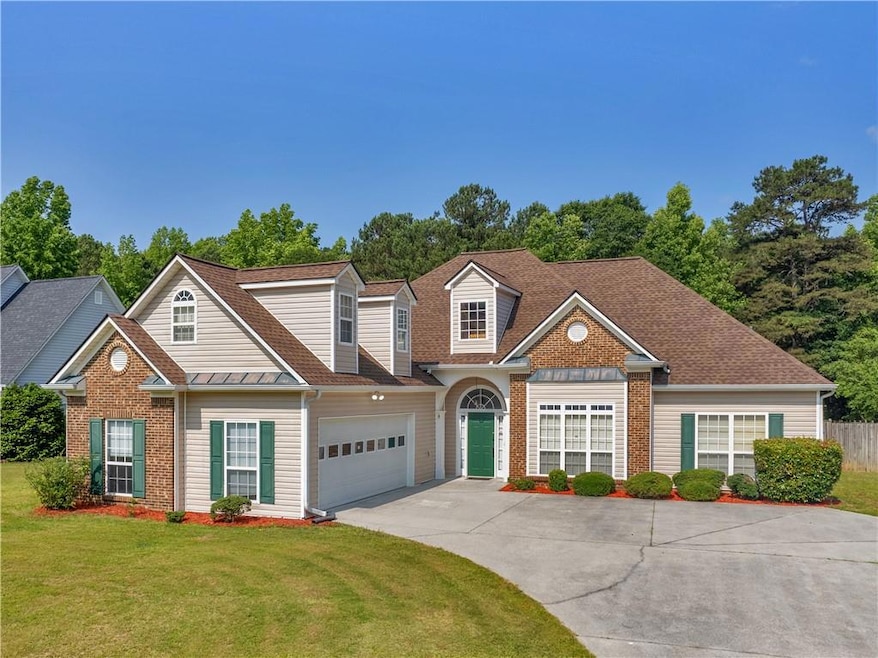Traditional-style home featuring driveway, brick siding, an attached garage, and roof with shingles
