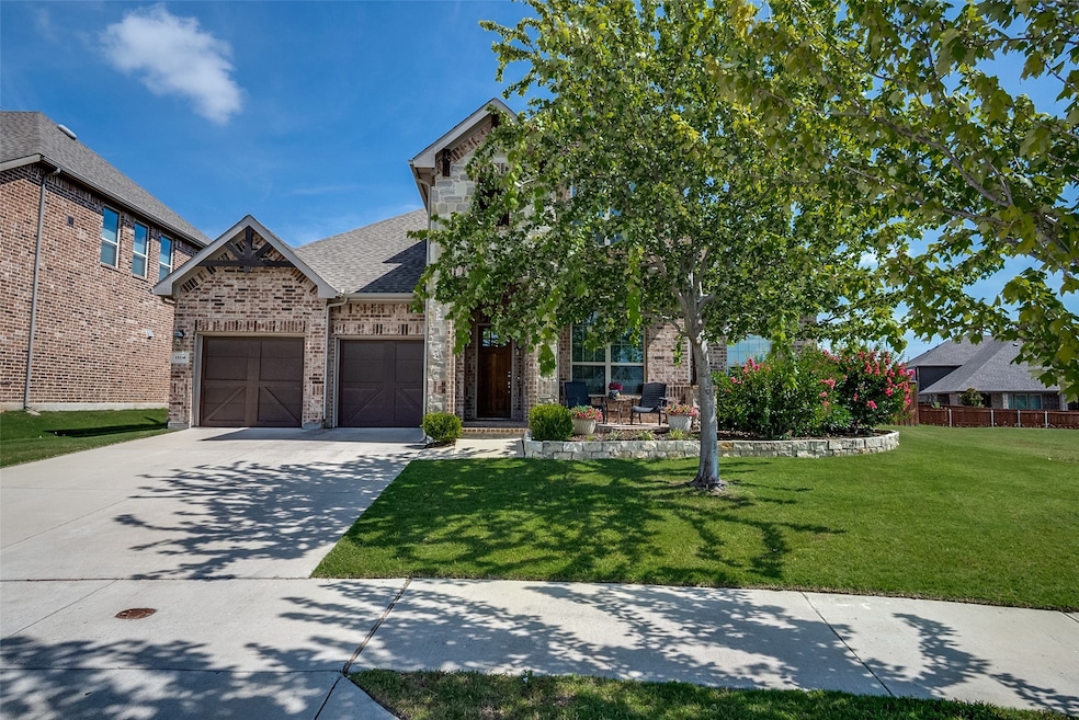 View of front facade featuring a front lawn, brick siding, driveway, a shingled roof, and an attached garage