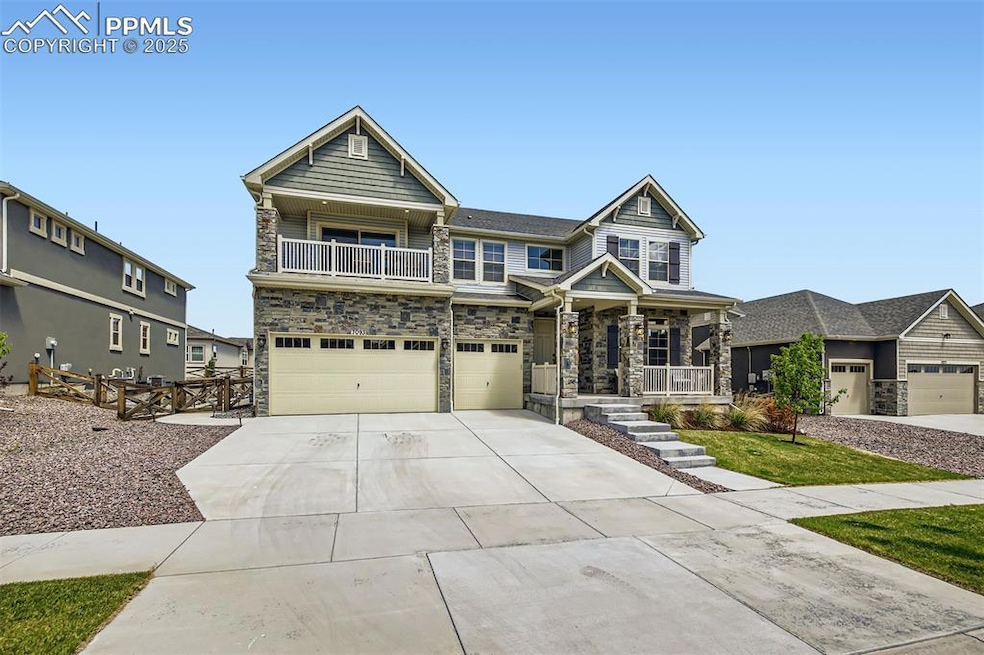 View of front of property featuring concrete driveway, covered porch, stone siding, a balcony, and an attached garage