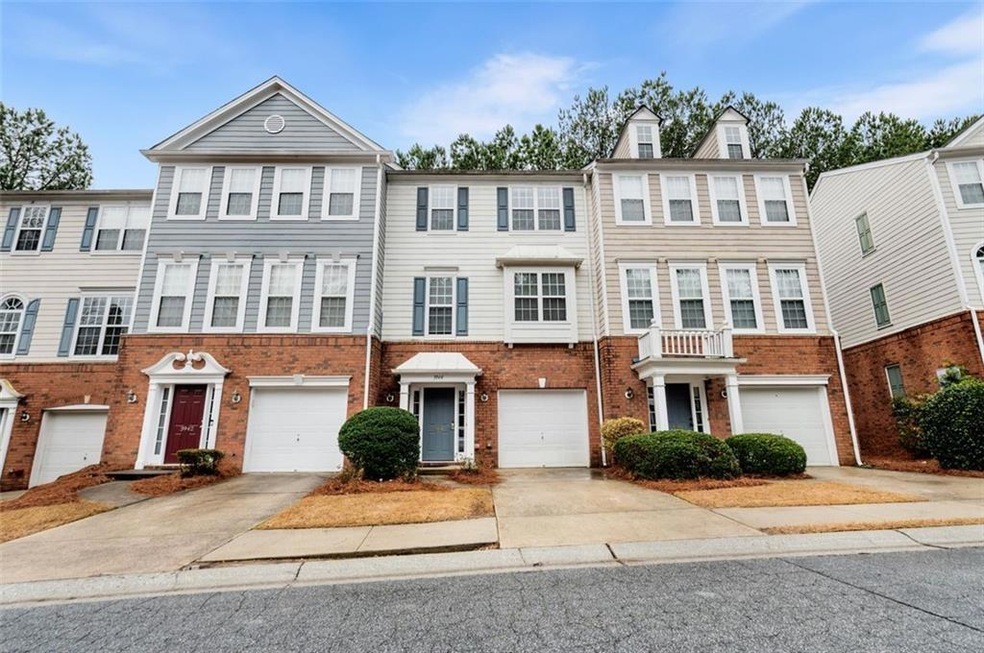 View of property with driveway, brick siding, and a garage