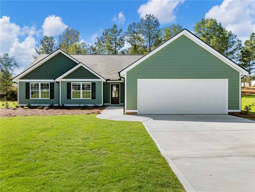View of front of property featuring concrete driveway, a garage, and a front lawn