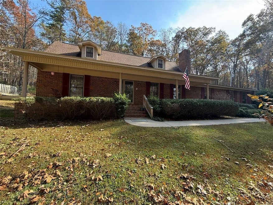 View of front of property featuring covered porch, a front lawn, brick siding, and a chimney
