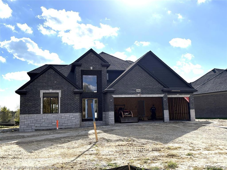View of front of house with stone siding, brick siding, an attached garage, and driveway