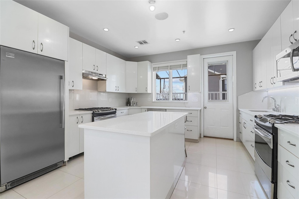 Kitchen featuring stainless steel appliances, decorative backsplash, light countertops, white cabinetry, and recessed lighting