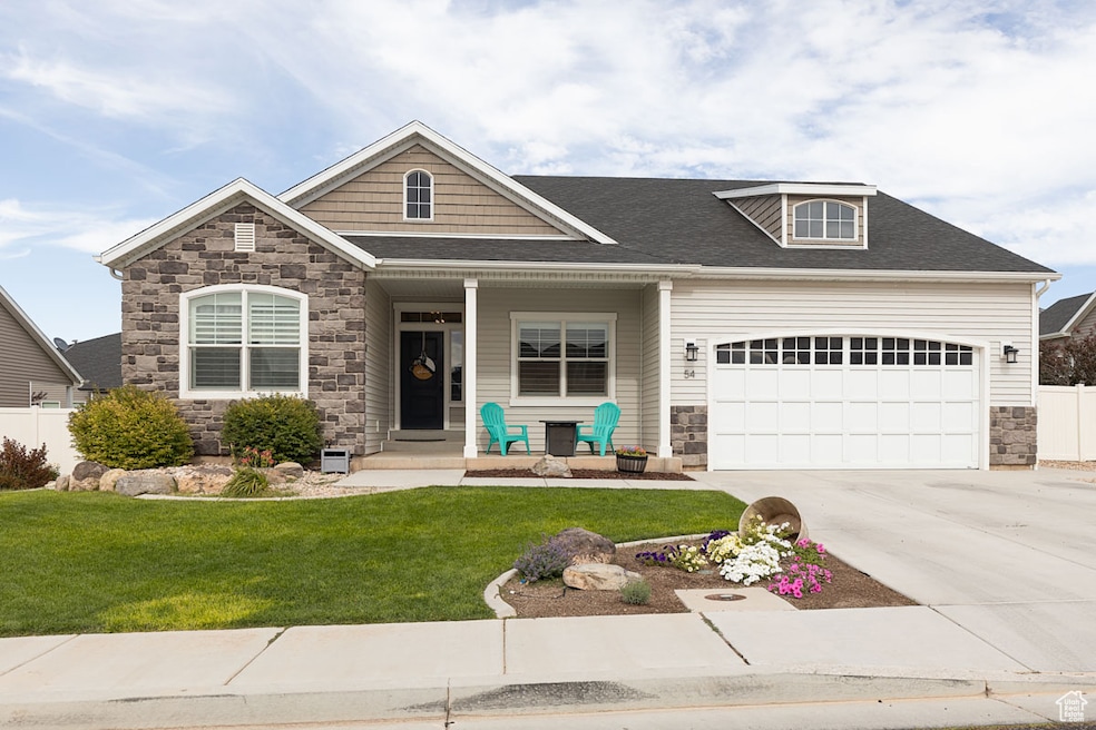 Craftsman-style house featuring stone siding, driveway, an attached garage, and covered porch