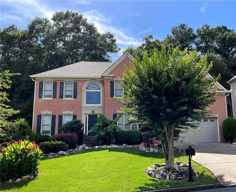 Colonial-style house featuring driveway, brick sid