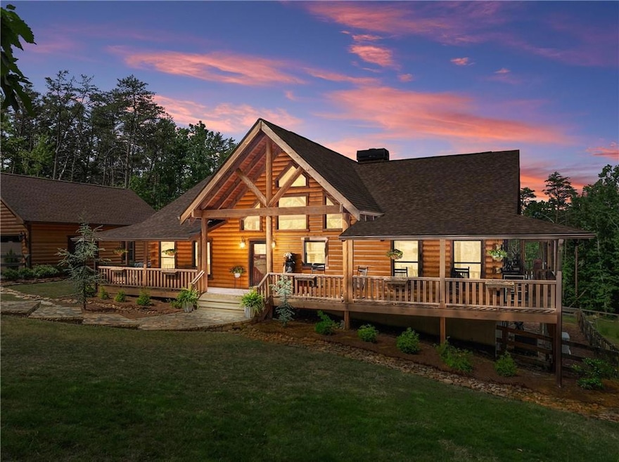 Back of house at dusk with roof with shingles, a yard, and a deck