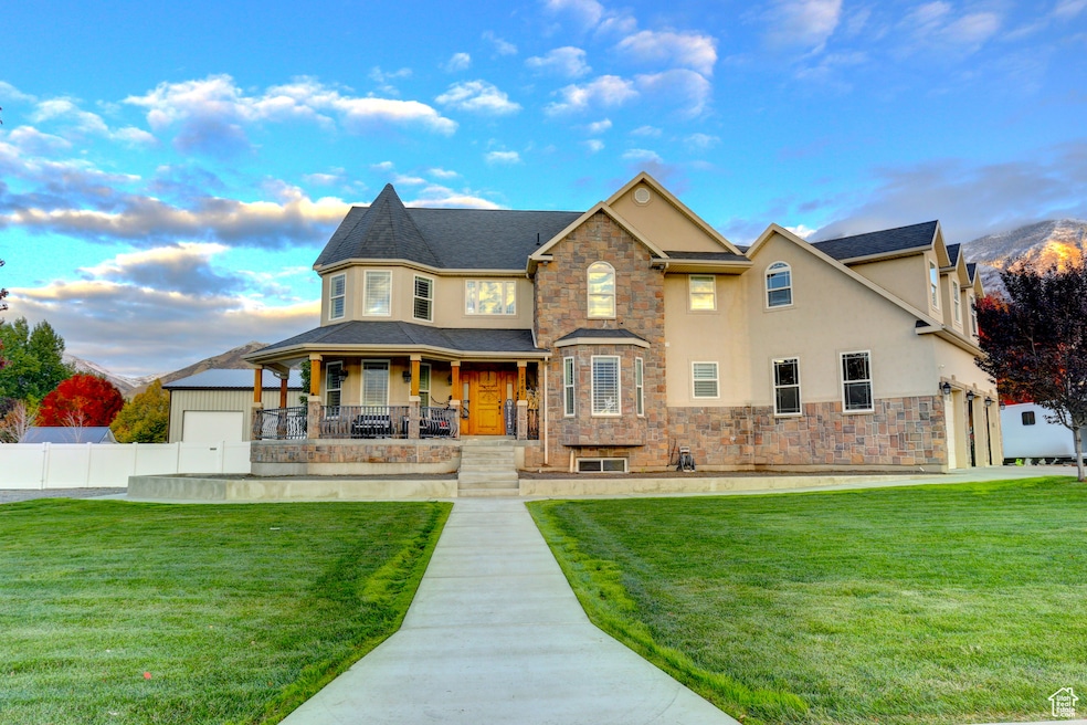 View of front of house featuring a porch, stucco siding, stone siding, and a garage