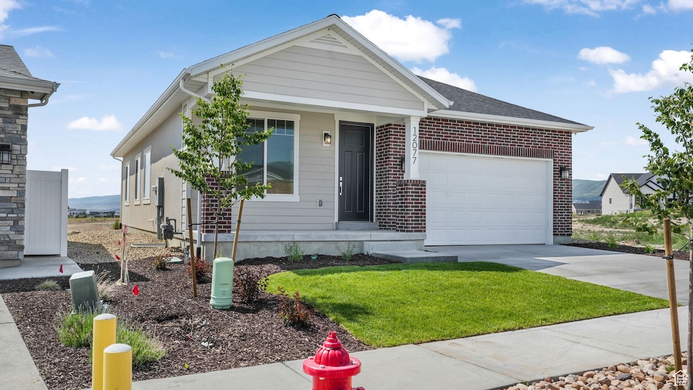 Single story home featuring an attached garage, concrete driveway, brick siding, and a front yard