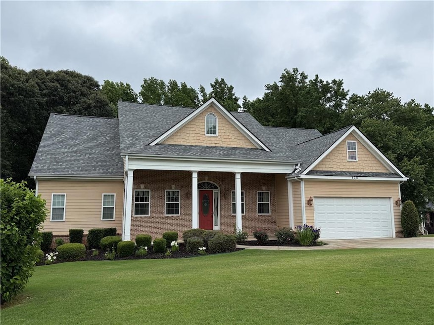View of front facade with a front lawn, an attached garage, a shingled roof, and concrete driveway