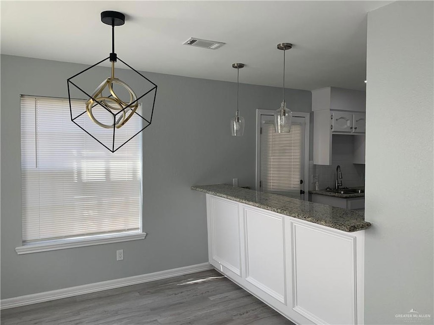 Kitchen featuring light wood-style floors, white cabinetry, hanging light fixtures, backsplash, and a chandelier