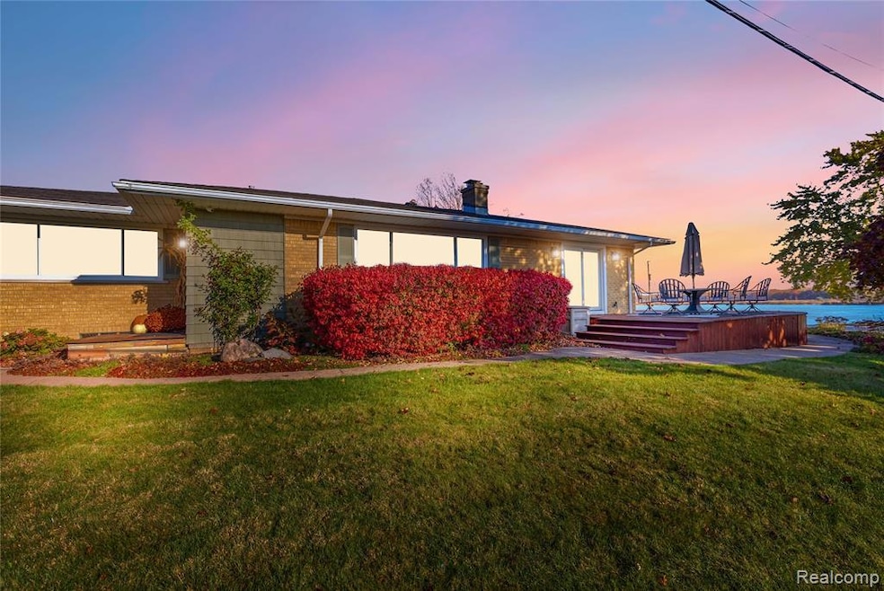 side view of property, with brick siding, chimney, landscaping,  front porch, and wrap around deck