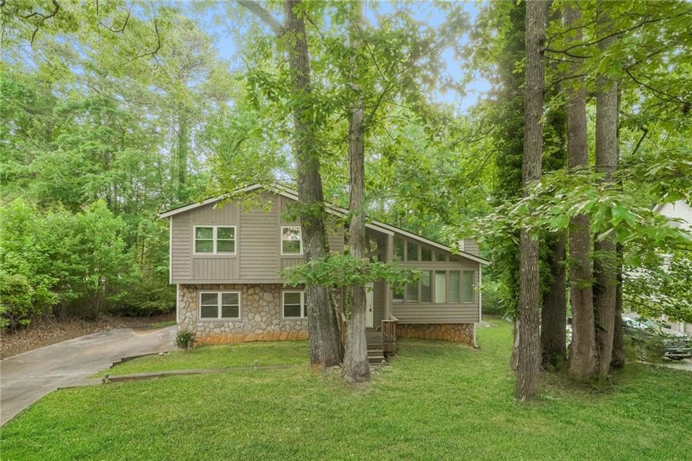 View of front facade featuring stone siding, a front lawn, and concrete driveway