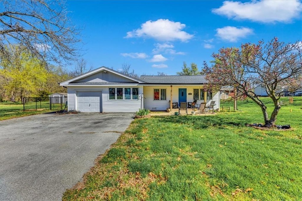Ranch-style house with a porch, a front lawn, and a garage