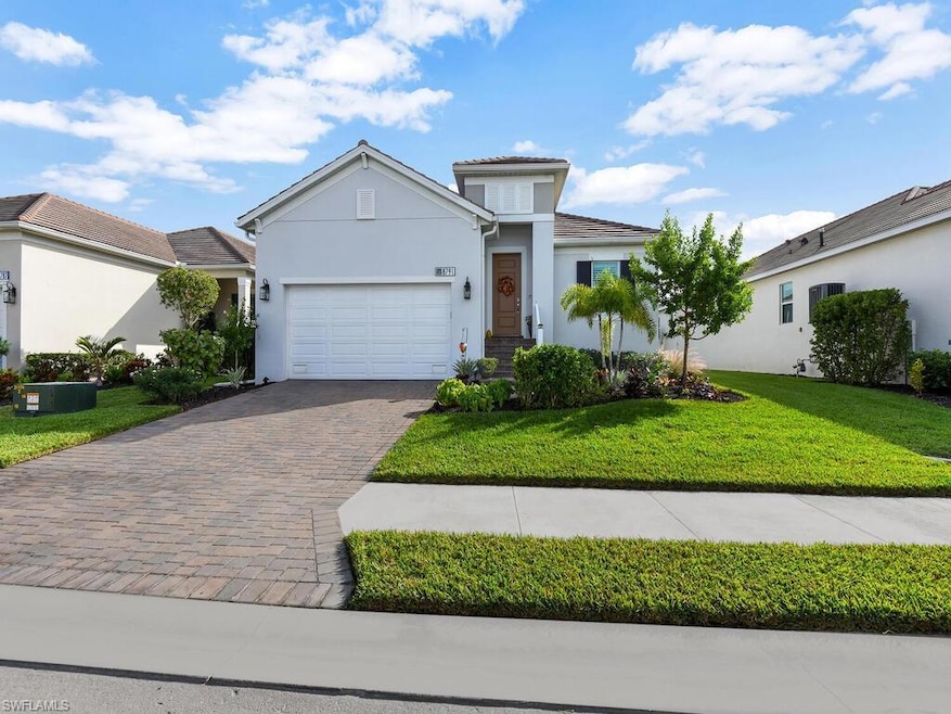 View of front of house with stucco siding, decorative driveway, a front yard, and a garage
